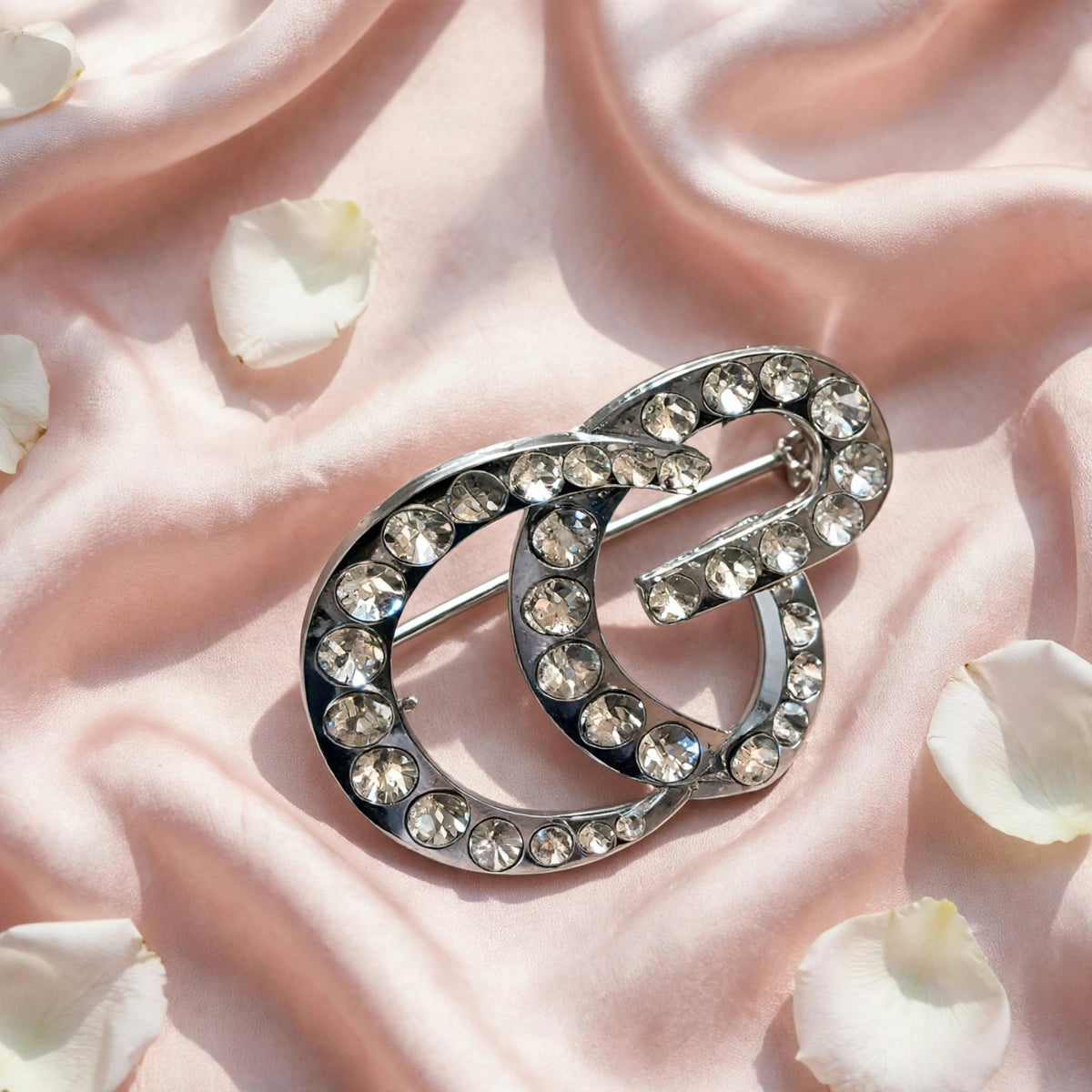 Buckle brooch flat lay on blush silk
