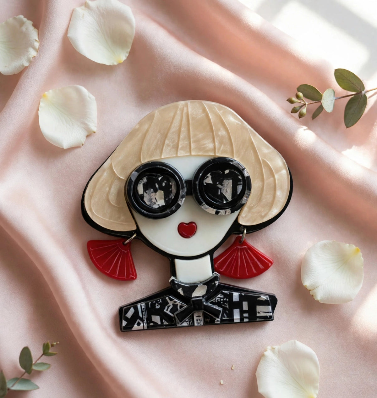 Fashionista brooch flat lay on blush silk