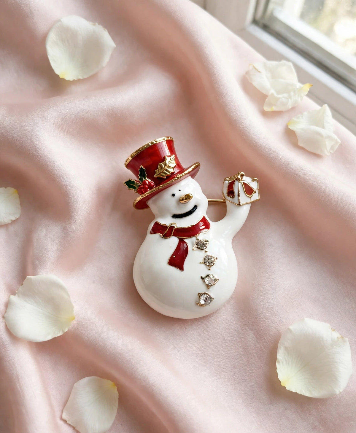 Snowman brooch flat lay on blush silk